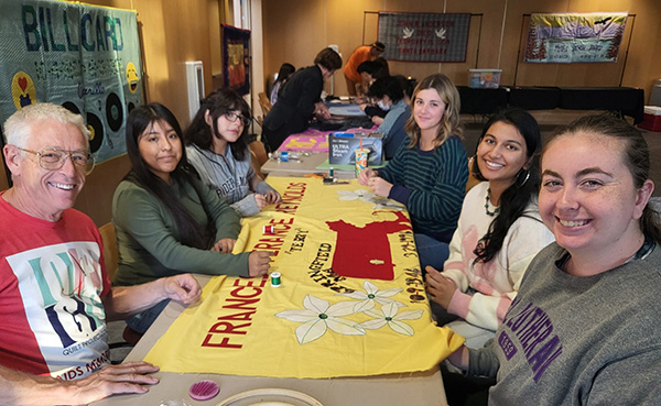 CLU Quilting Bee group photo of members working on quilts at a long table