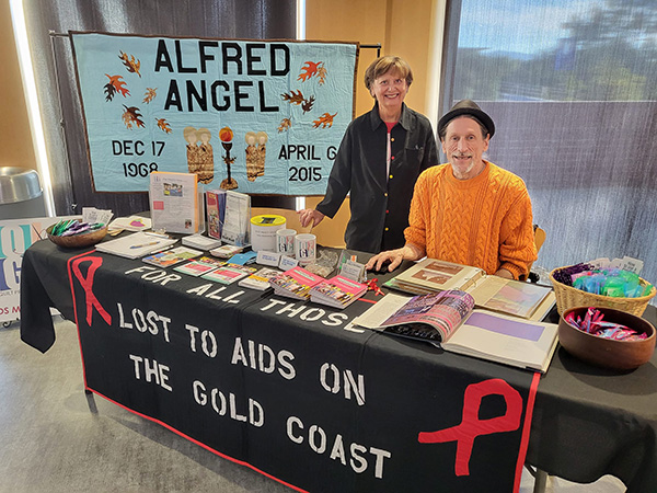 CLU World AIDS Day display booth with quilts on display and QPGC members Neil and Celia