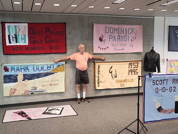 Volunteer Mark Lager appears in front of quilts on display